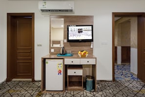 A small kitchenette with a refrigerator, a microwave, a sink, and a television mounted above it. - ADDRESS AJYAD HOTEL (Makkah)