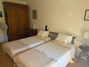 A bedroom with two beds, a wooden wardrobe, a bedside table, a lamp, and a wall decoration. - Bed and Breakfast 'Chambres Les Chats' with Mountain View, Shared Garden and Wi-Fi (Châteaudouble)