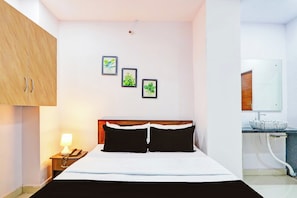 A hotel room with a bed, a nightstand with a lamp and phone, a wooden wardrobe, and a bathroom with a sink and mirror. - Hotel O Karmanghat Near TKR khaman (Hyderabad)