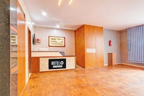 A hotel reception area with a wooden reception desk, a framed picture of a dove, a fire extinguisher, and a ceiling fan. - Hotel O Karmanghat Near TKR khaman (Hyderabad)