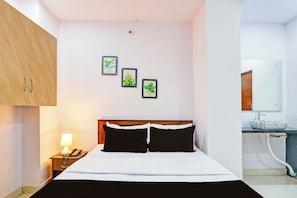 A hotel room with a bed, a nightstand with a lamp, a telephone, and a bathroom with a sink and mirror. - Hotel O Karmanghat Near TKR khaman (Hyderabad)