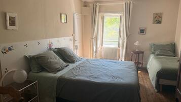 Una camera da letto con un letto, una sedia, un tavolo e una finestra con tende.