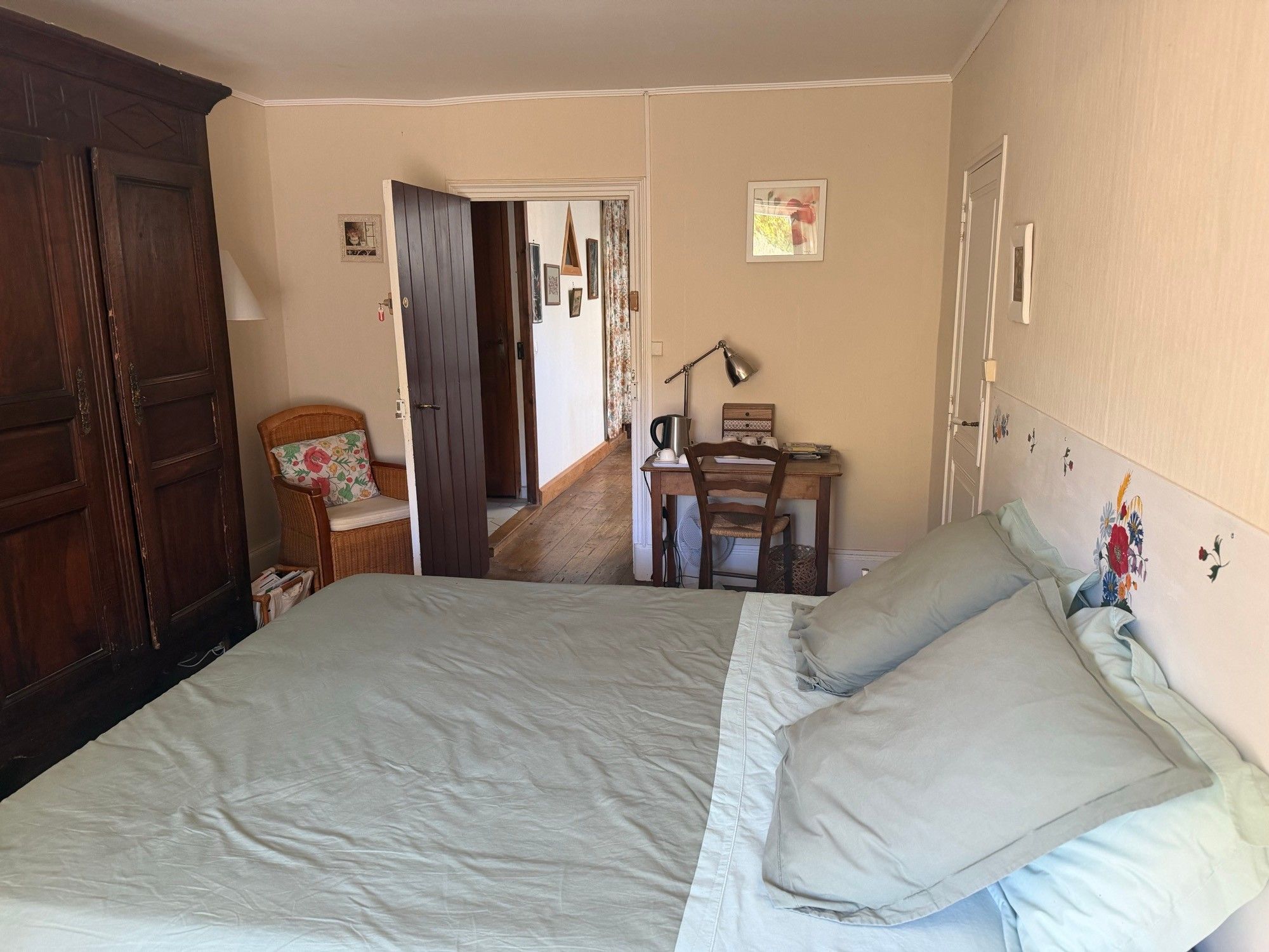 Une chambre à coucher comprenant un lit, une chaise, un bureau et une porte donnant sur une autre pièce.