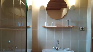Un bagno con un lavandino su piedistallo, uno specchio rotondo e due applique.