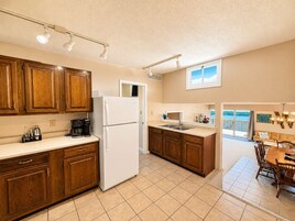 Una cocina con armarios de madera, un refrigerador blanco y un comedor con mesa y sillas.