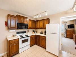 Una cocina con armarios de madera, estufa, microondas y refrigerador.