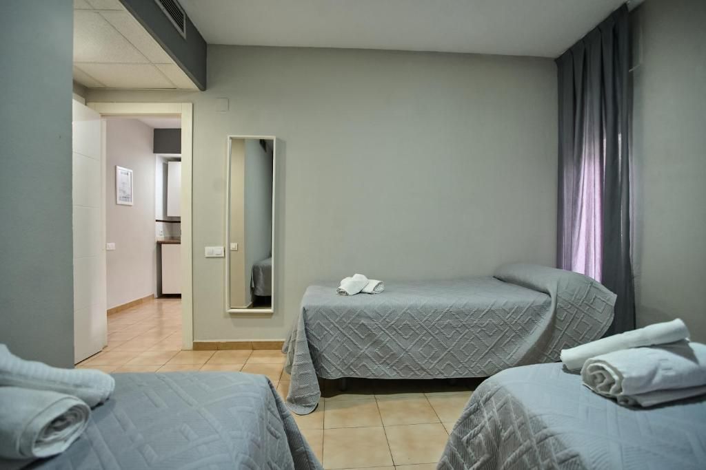 A hotel room with two beds, a mirror, and a bathroom visible through an open door.