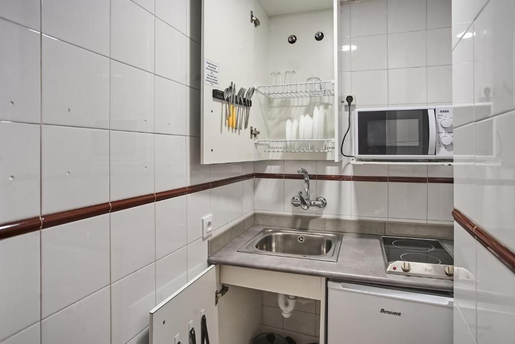 Una cocina funcional con microondas, pileta y estufa.