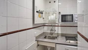 Una cocina funcional con microondas, pileta y estufa.