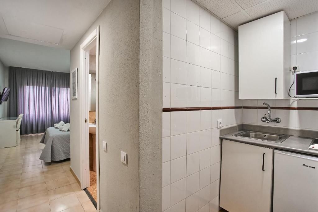 A compact hotel room with a kitchenette, a bed, and a bathroom.
