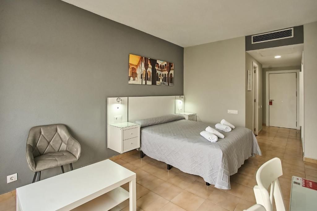 Une chambre à coucher avec un lit, des tables de chevet, une chaise et un bureau.