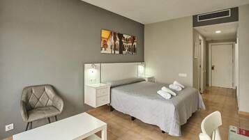 Une chambre à coucher avec un lit, des tables de chevet, une chaise et un bureau.