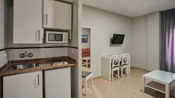 A compact kitchen with a microwave, sink, and refrigerator. There is a small dining area with a table and chairs.
