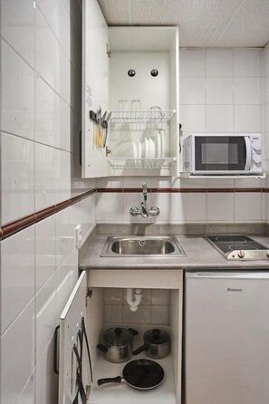 A compact kitchen with a microwave, sink, and storage cabinets.