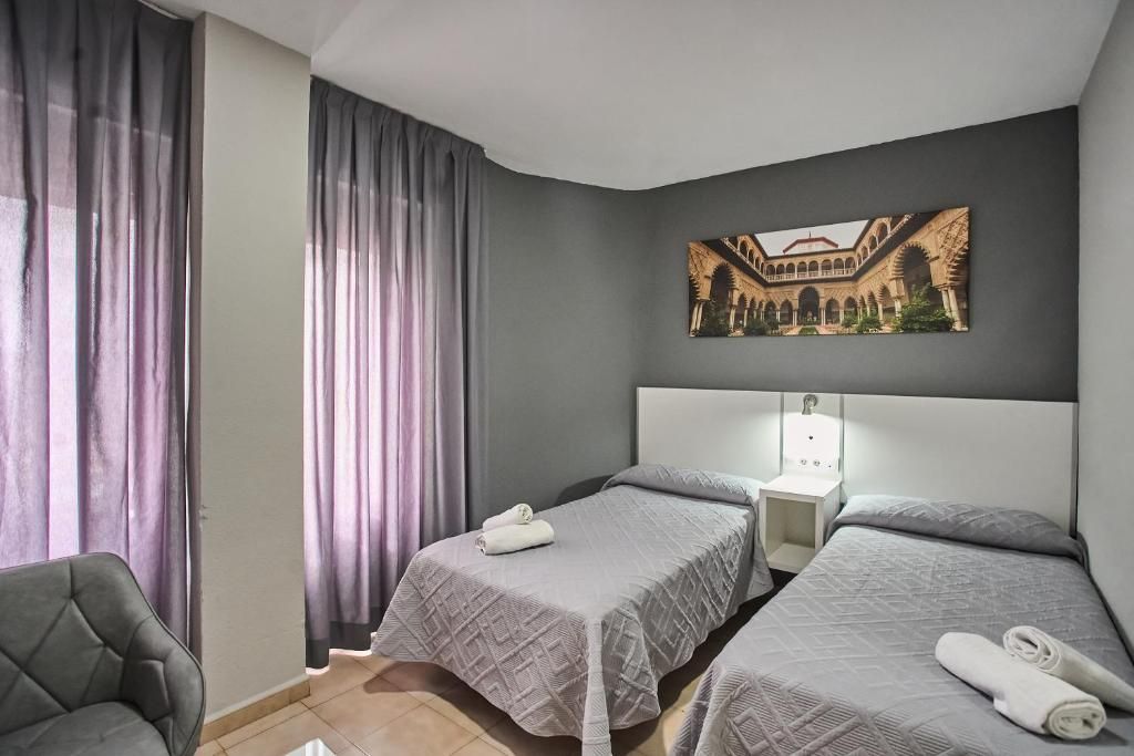 Une chambre d’hôtel avec deux lits, une table de chevet, une chaise et un tableau au mur.
