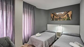 Une chambre d’hôtel avec deux lits, une table de chevet, une chaise et un tableau au mur.