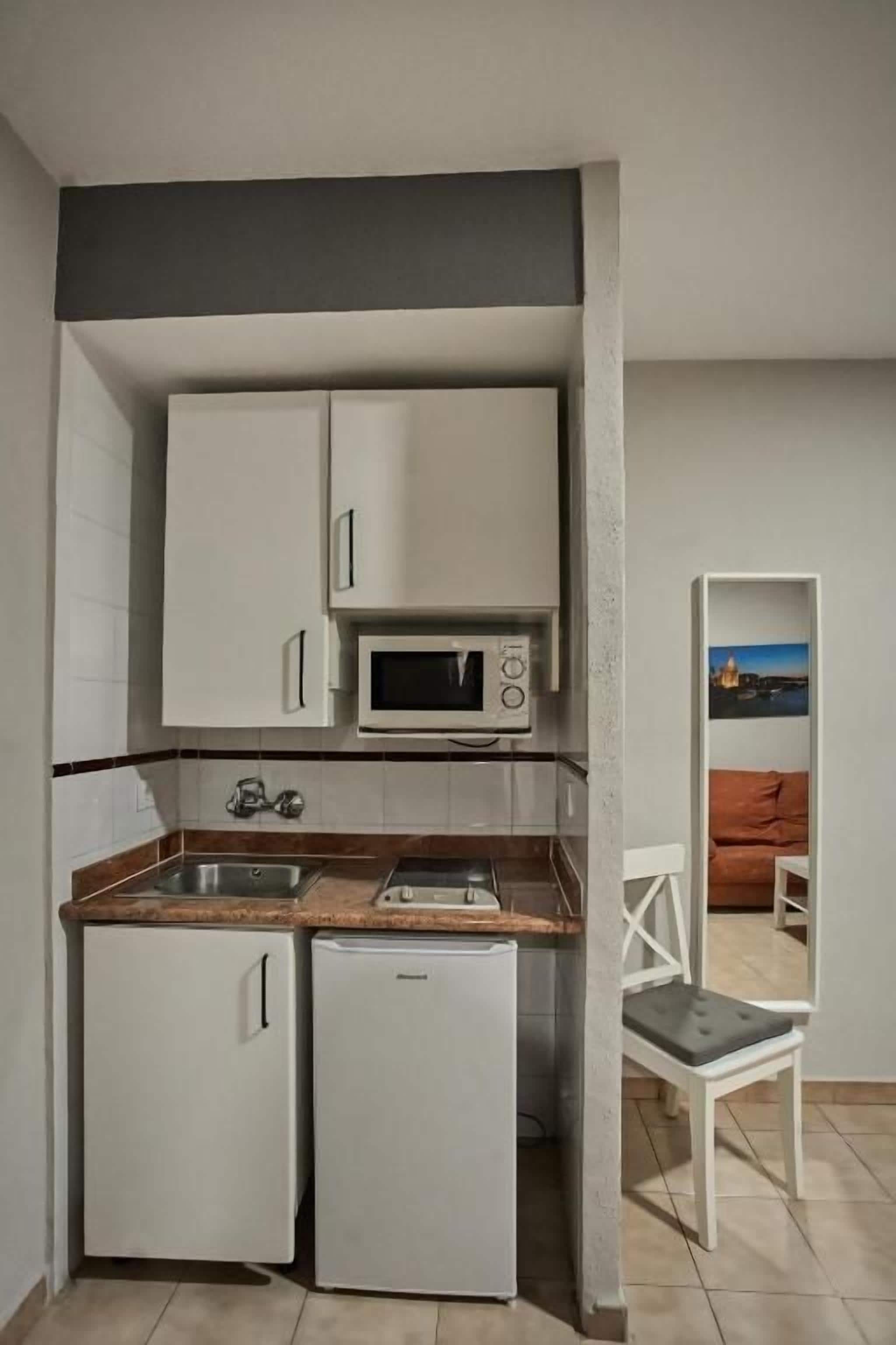 A compact kitchenette with a microwave, two small refrigerators, and a sink.