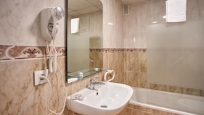 Un baño con lavamanos blanco, secador de pelo y bañera.