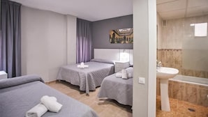 Habitación de hotel con dos camas, baño con lavamanos y bañera, y un cuadro en la pared.