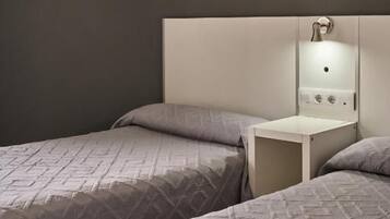 A hotel room with two beds, a nightstand, and a wall-mounted artwork.