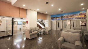 Un vestíbulo con asientos, una escalera y un mural de un paisaje urbano.