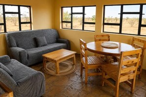 A room with a sofa, a round wooden table with chairs, and large windows with a view of the outdoors. - Perfect 3-bedroom house in nice Kajiado County location (Kajiado County)