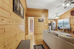A wooden interior with a sofa, dining table, and kitchen area. - Bear Essentials & Hot Tub (Blairsville)