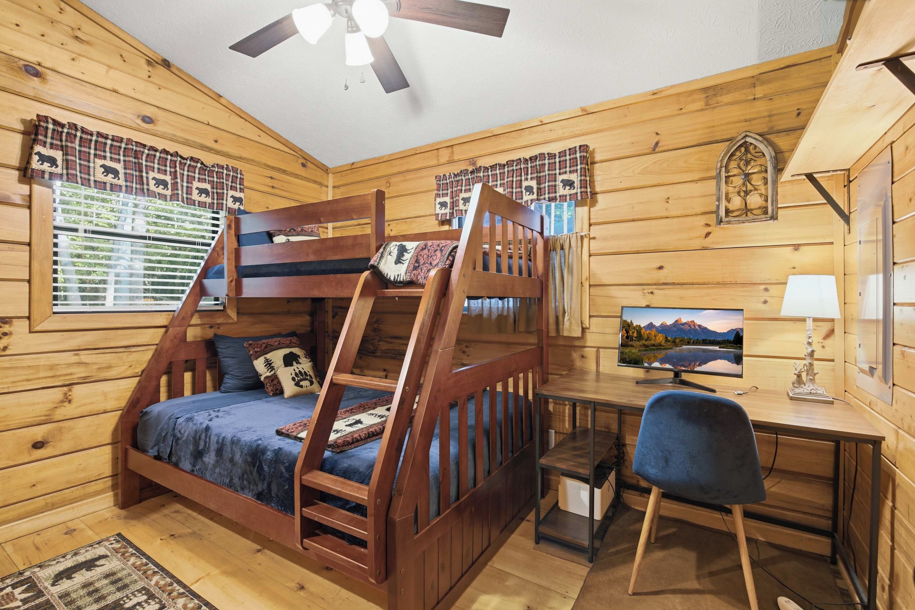 A cabin with a bunk bed, a desk with a computer, and a chair.
