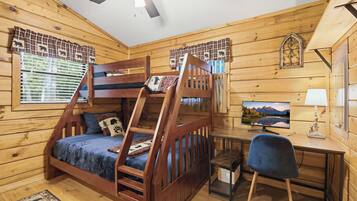 A cabin with a bunk bed, a desk with a computer, and a chair.