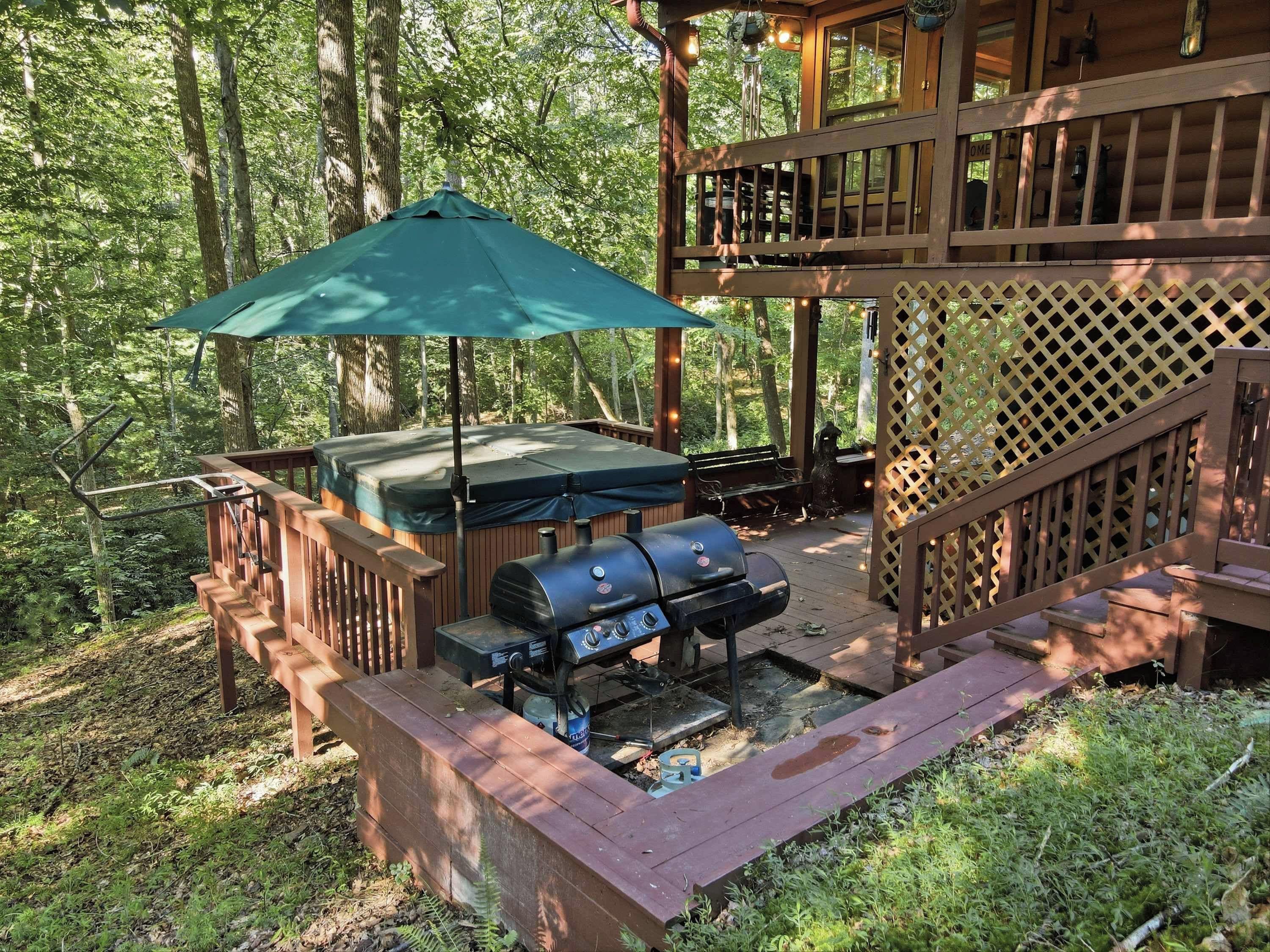 A covered outdoor barbecue area with a grill and seating, surrounded by a wooden deck and a lattice fence.