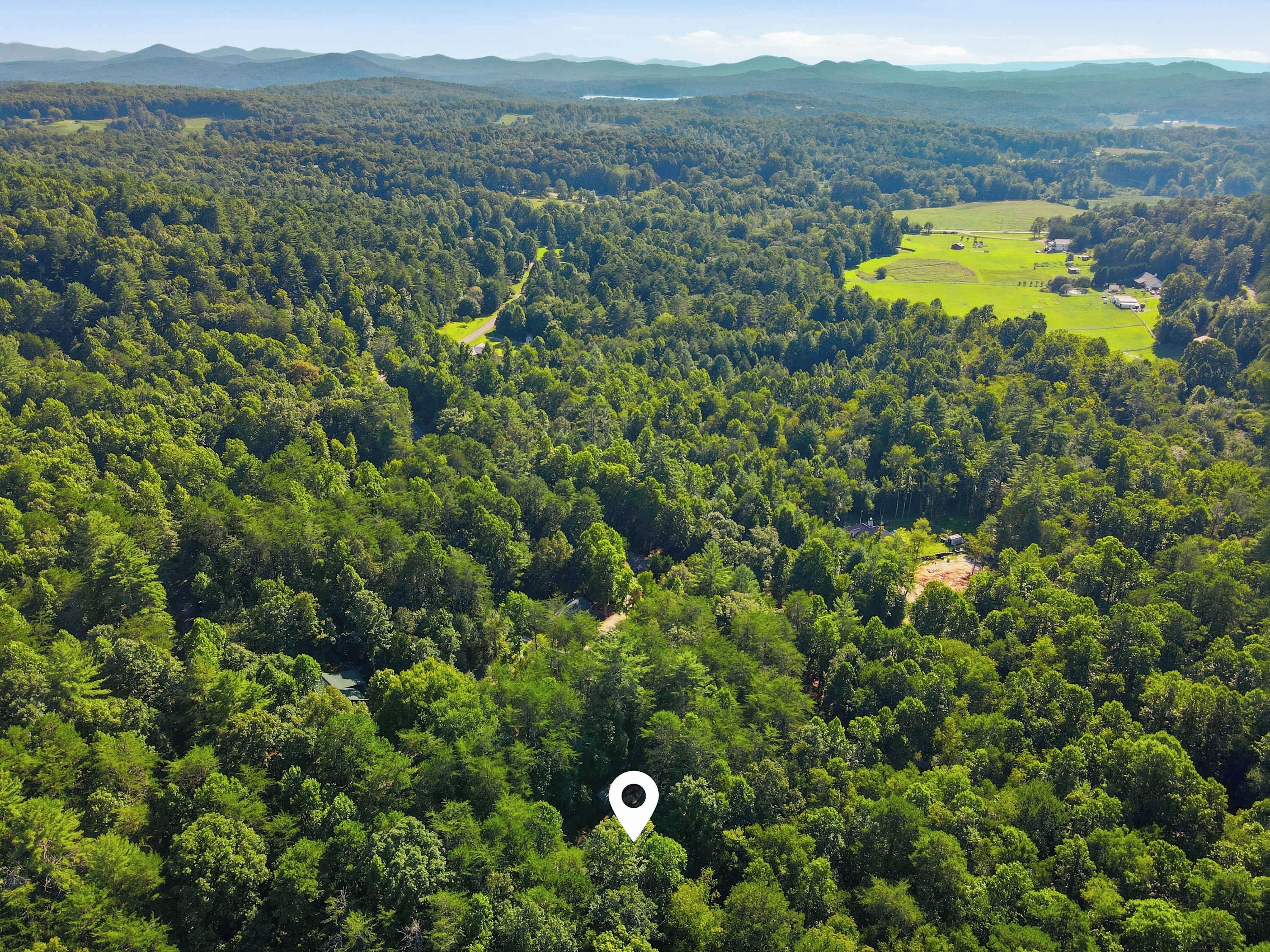 An aerial view of a forested area with a clear path and a small building.
