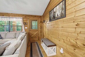 A cozy cabin interior with a wooden exterior, a sofa, a bench, and a framed picture on the wall. - Bear Essentials & Hot Tub (Blairsville)