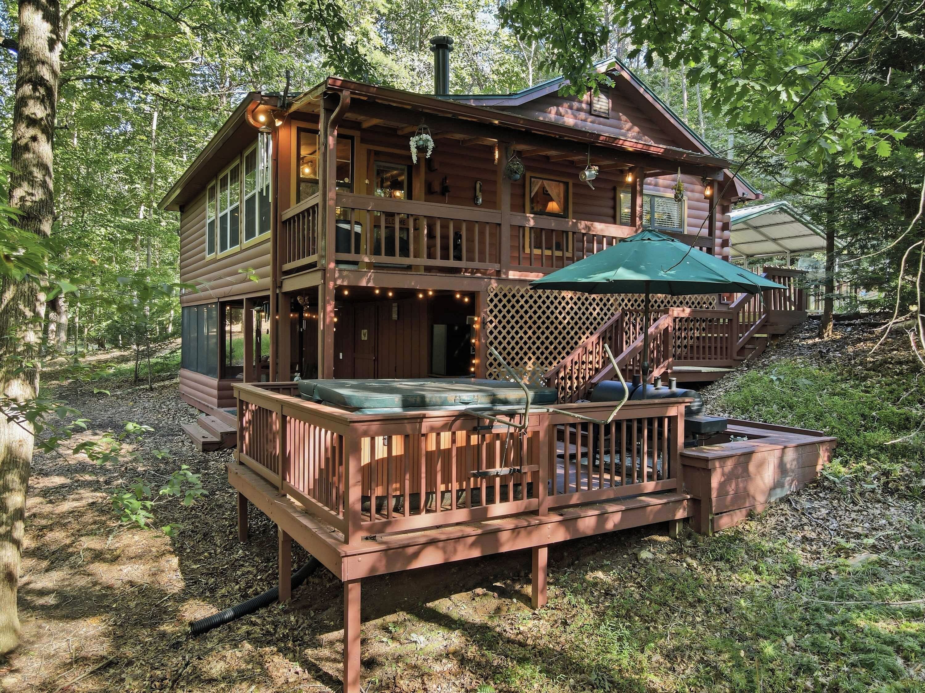 A cabin with a deck, outdoor seating, and a staircase leading to an upper level.