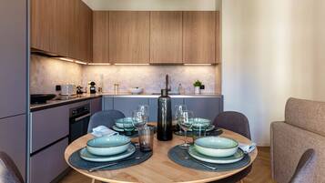 A modern kitchen with wooden cabinets, a dining table set with plates, glasses, and cutlery.