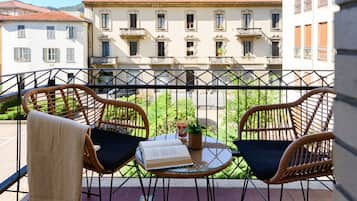 Un balcone con sedie in vimini, un tavolino e un libro.