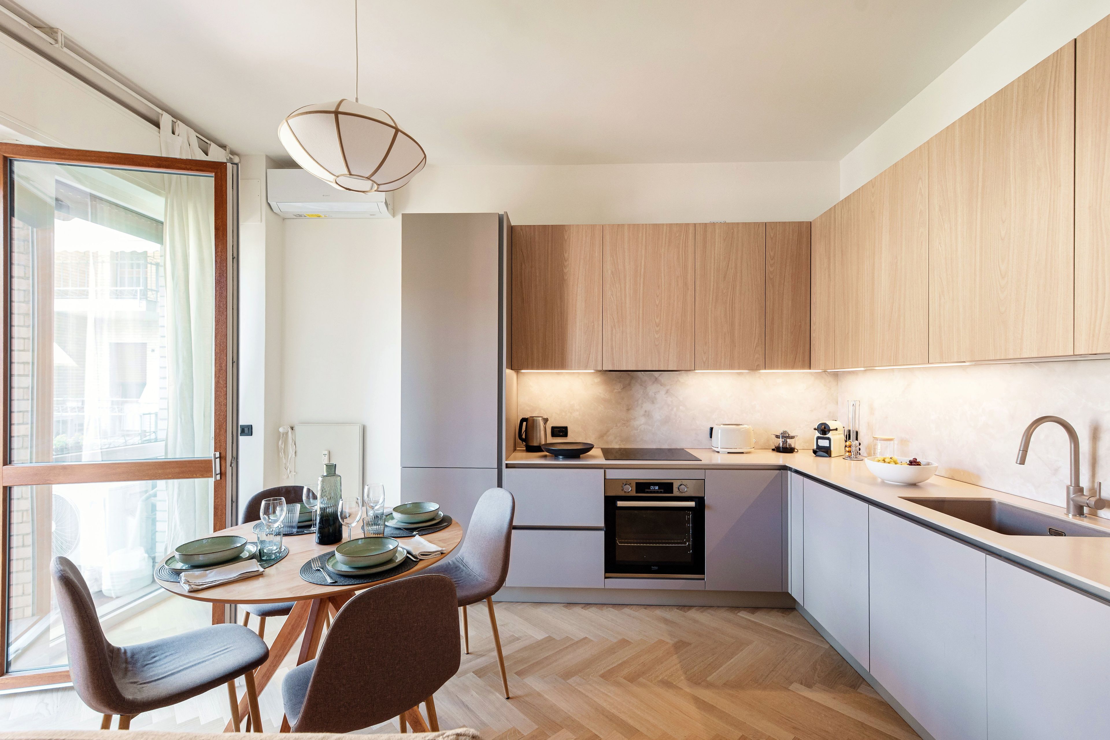 Una cucina moderna con zona pranzo, dotata di forno integrato, lavello e tavolo imbandito per quattro persone.