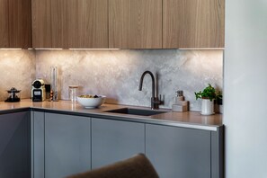 Una cocina moderna con un lavamanos integrado, armarios de madera y un salpicadero de mármol.
