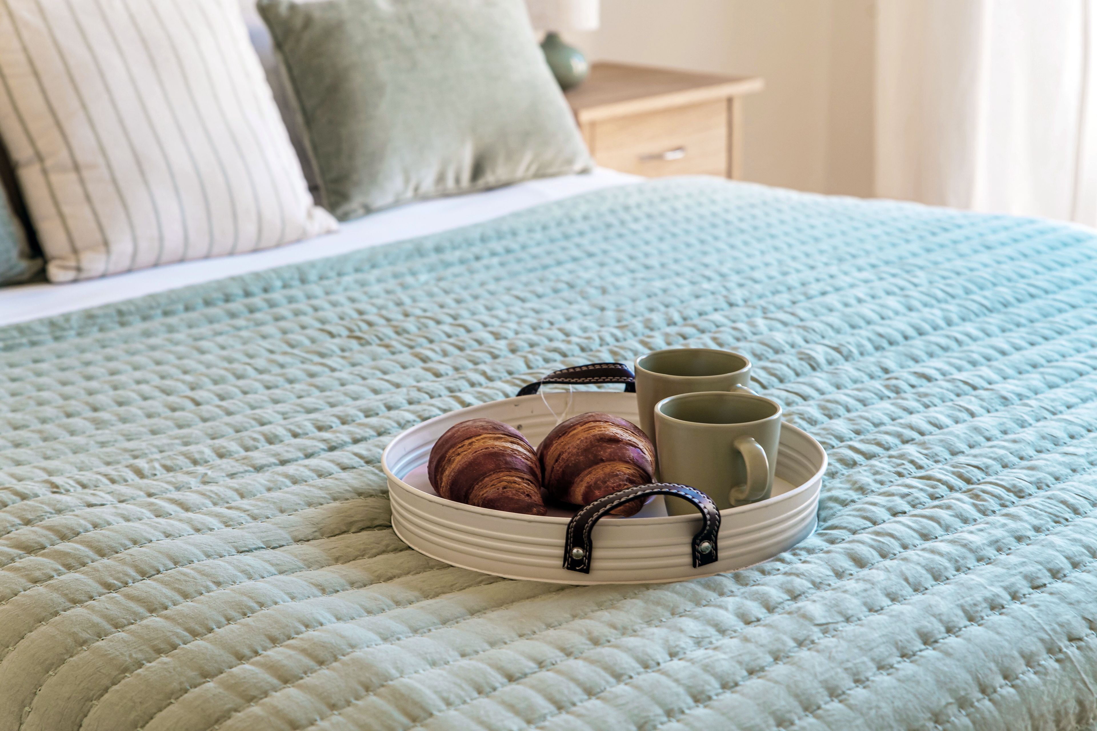 A bed with a quilted bedspread, a bedside table with a lamp, and a nightstand with a lamp.