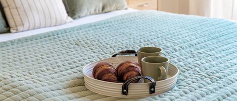 A bed with a quilted bedspread, a bedside table with a lamp, and a nightstand with a lamp.