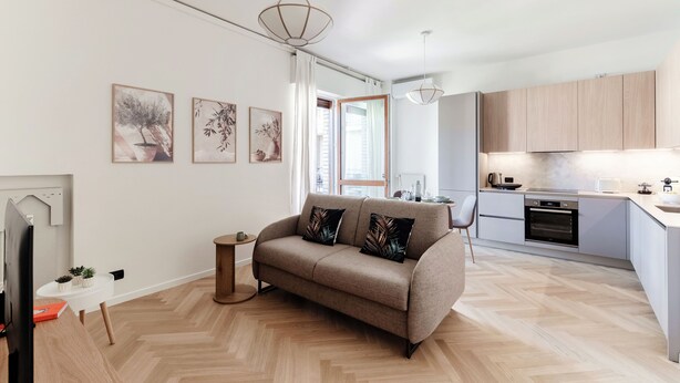A modern living room with a sofa, a dining table, and a kitchen area with cabinets and appliances. - Otium Lake Como (Como)