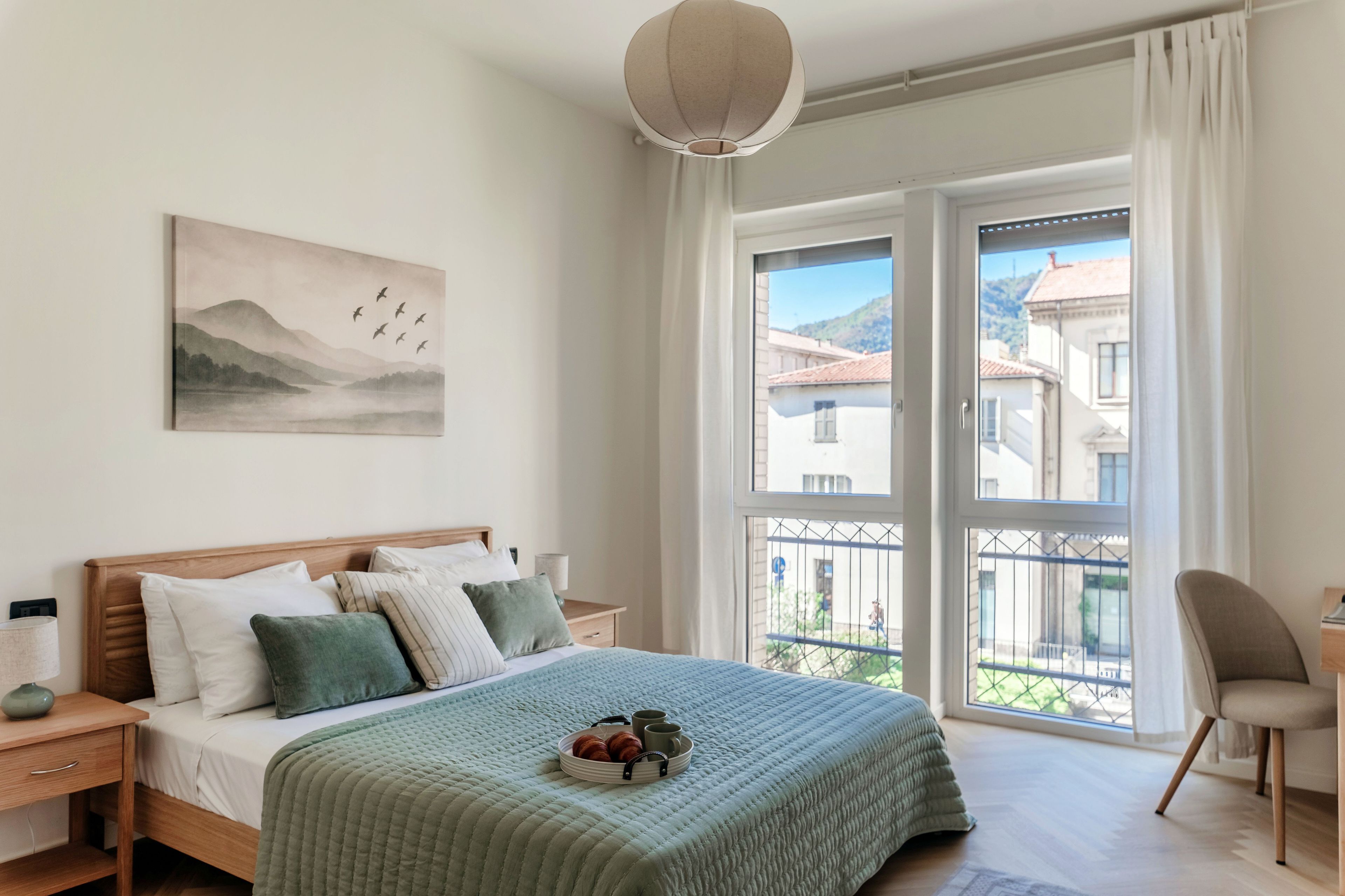 A bedroom with a bed, bedside table, lamp, and a painting on the wall.
