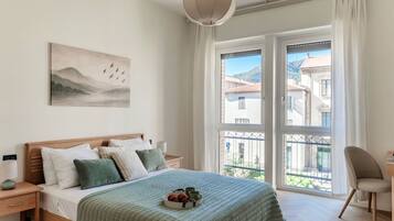 A bedroom with a bed, bedside table, lamp, and a painting on the wall.
