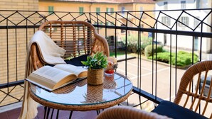 A balcony with wicker furniture, a glass table, a book, and a potted plant. - Otium Lake Como (Como)