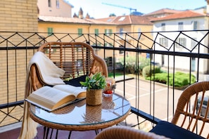A balcony with wicker furniture, a glass table, a book, and a potted plant. - Otium Lake Como (Como)