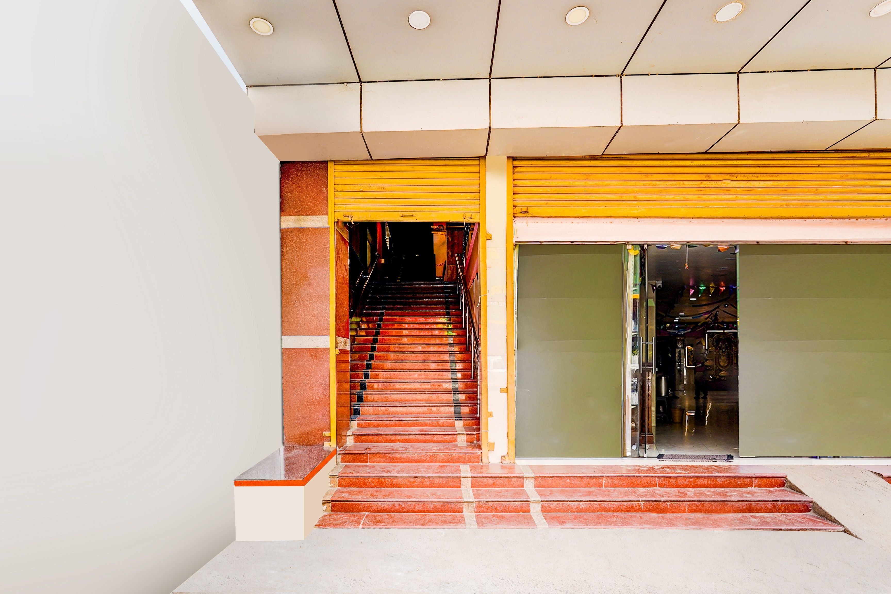 Un escalier menant à l’entrée d’un magasin, avec un volet jaune et une porte en verre.