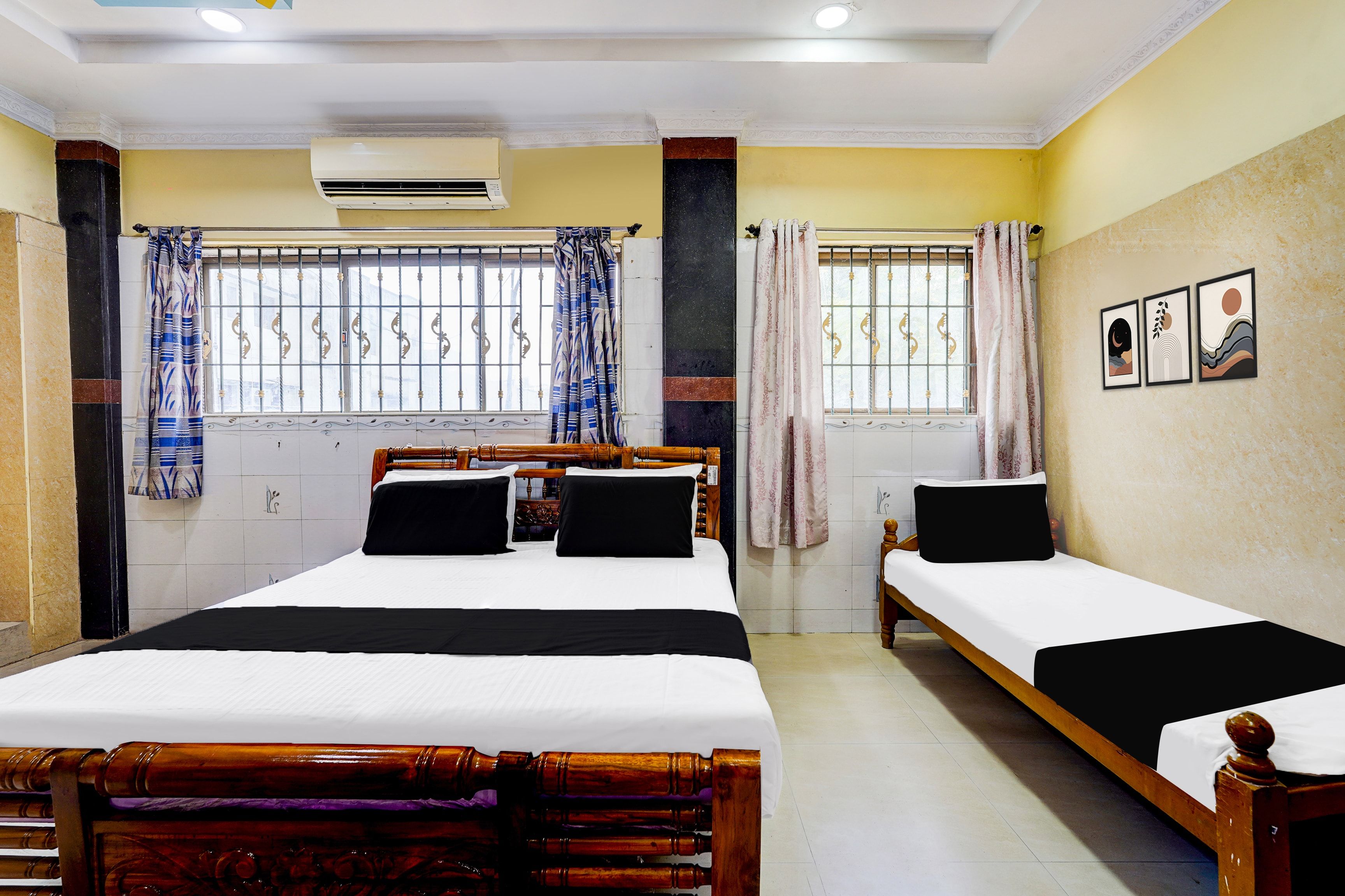 Une chambre d’hôtel avec deux lits, une fenêtre avec des barreaux en métal et un appareil de climatisation.