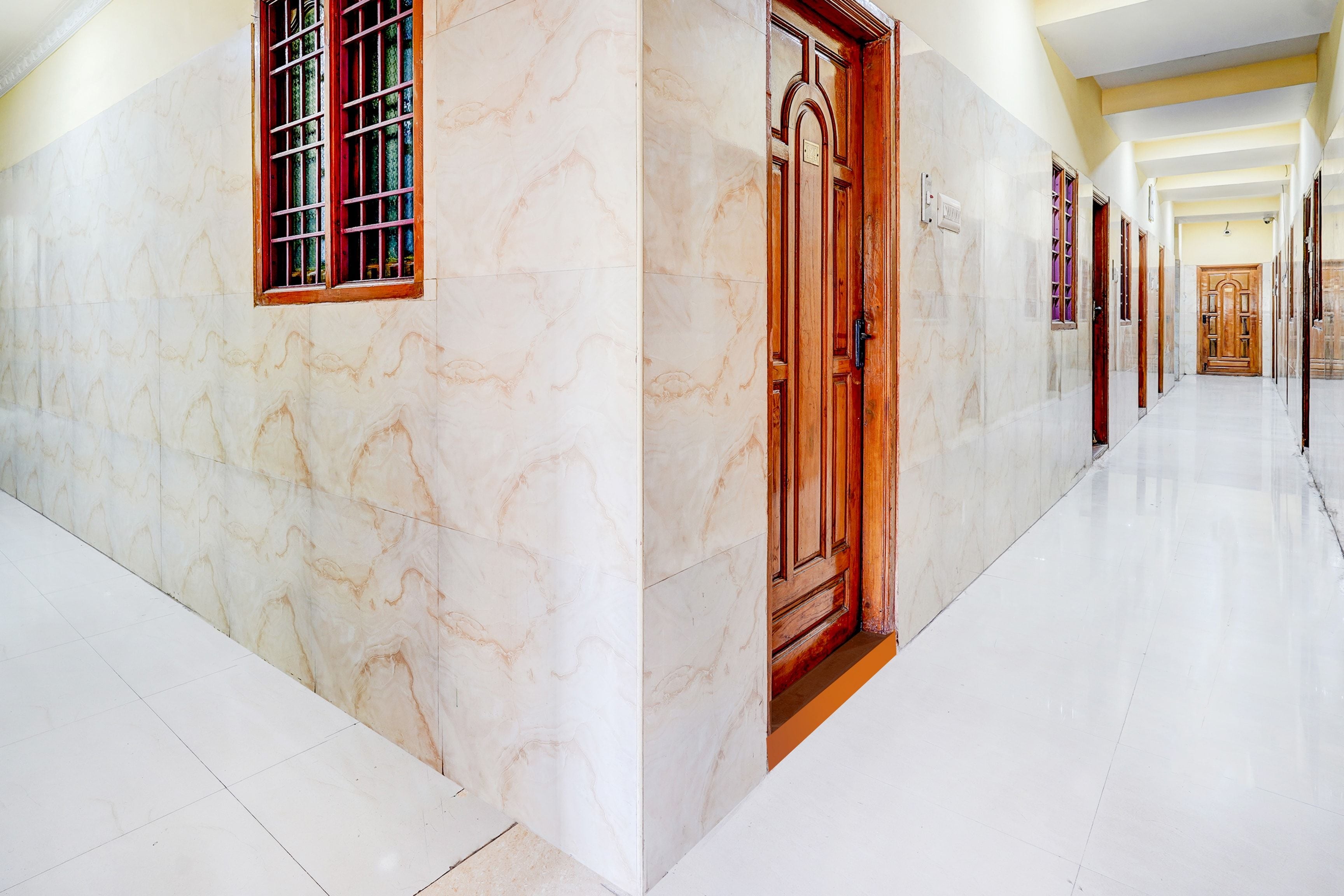 A corridor with marble walls and a wooden door.