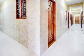 A corridor with marble walls and a wooden door. - Hotel O Manali Crossway Chennai (Chennai)