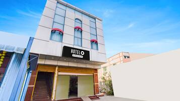 Un hotel anomenat 'HOTELO' amb una façana moderna, una entrada ben visible i un cel serè.