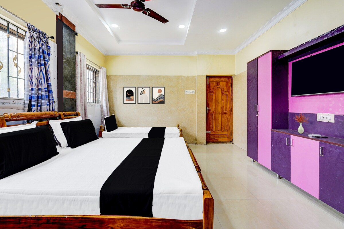 A hotel room with two beds, a ceiling fan, a window with curtains, a door, and a purple wardrobe.